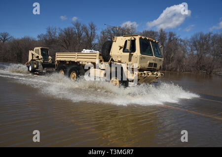 A North Dakota Army National Guard Light Medium Tactical Vehicle drives through flood water covering the highway near the Sheyenne River April 8, 2019 in Grand Forks, North Dakota. The record flooding is expected to worsen as a late winter storm barrels into the midwestern United States over the next few days. Stock Photo