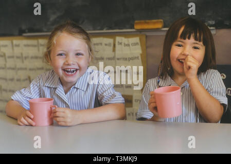 Two smiling schoolgirls at break time with a drink. England, UK Stock Photo