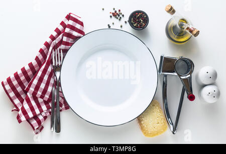 white enamelled empty plate on the table with a red checkered napkin and parmesan cheese with its grater. Typical Mediterranean style Stock Photo