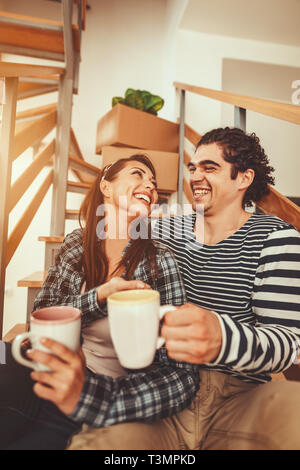 The young couple is moving into a new house. They are resting after bringing boxes with things to their new home. Stock Photo