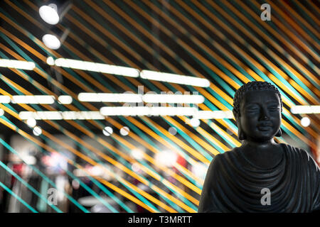 Bust of Buddha in illuminated interior with colorful ropes lines installation Stock Photo