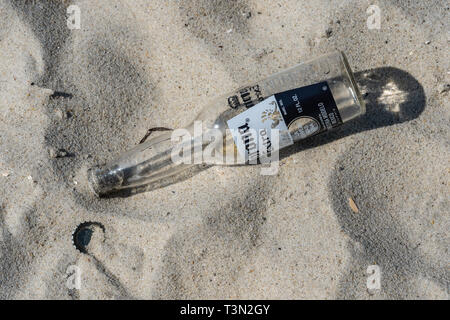 Wantaugh, NY - August 21, 2018: Empty Corona Extra bottle and cap is discarded in the sand on the beach at Jones Beach. Stock Photo
