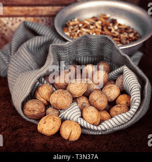 Whole walnuts in bag on the background walnut kernels in the bowl Stock Photo