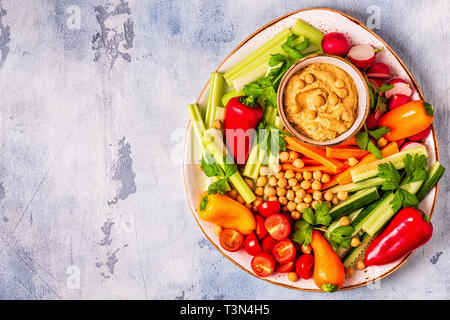 Hummus with various fresh raw vegetables, top view. Stock Photo