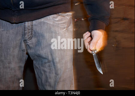 A young man holding a balisong or butterfly knife for protection on a street in Newport, South Wales.  09/07/2006 Stock Photo