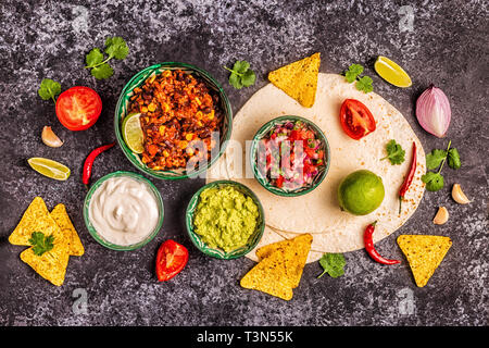 Mexican food concept: tortillas, nachos with guacamole, salsa, chili con carne, top view. Stock Photo