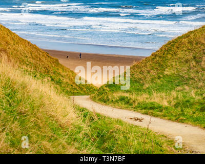 A steep bridle way for horse riders access down the cliff between Marske and Saltburn on the North Yorkshire Coast a man and his dog on the beach Stock Photo