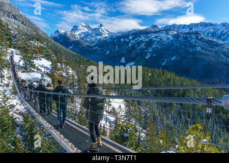 People walking across the Suspension Bridge on top of a mountain in Squamish, BC, Canada. Stock Photo