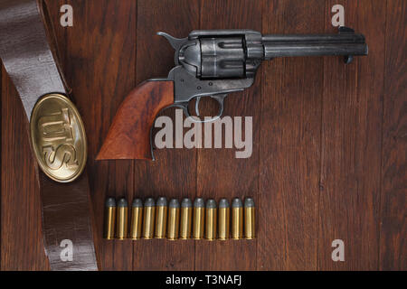 Old revolver with cartridges and U.S. Army soldier's belt with a buckle on wooden table Stock Photo