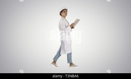 Young technician inspecting and taking necessary notes on digital tablet on gradient background. Stock Photo
