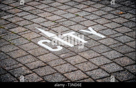 City sign with white arrow from letter I painted on the cobblestone in large megapolis city   Stock Photo