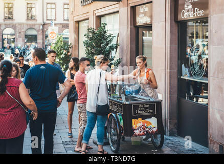 Strasbourg, France - Jul 22, 2017: Young blonde woman serving customer with french bio home-made ice-cream parlor in central Strasbourg France horizontal image Stock Photo