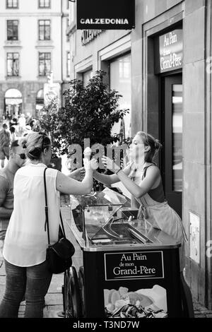 Strasbourg, France - Jul 22, 2017: Young blonde woman serving customer with french bio home-made - ice-cream parlor in central Strasbourg France - black and white Stock Photo