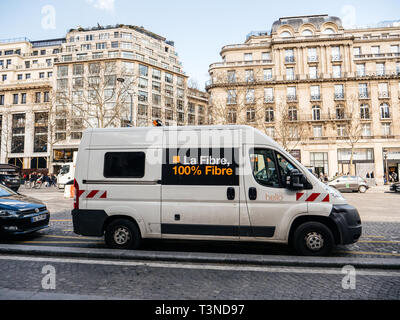 Paris, France - Mar 19, 2019: White Orange Telecom van with servicing fiber installation seen on Champs Elysee boulevard with luxury haussmannian buildings in background  Stock Photo