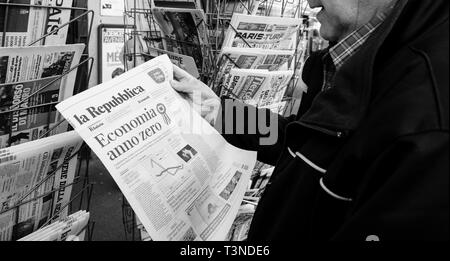 Paris, France - 29 Mar 2019: Newspaper stand kiosk selling press with senior male hand buying latest italian La republica featuring Economia anno zero on front cover black and white Stock Photo