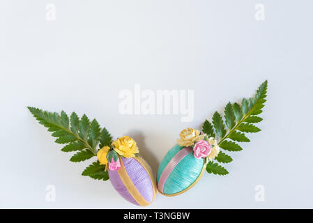 Vintage style handmade pastel Easter eggs and fern leaves on solid white background Stock Photo