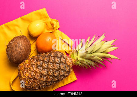 Composition of various fresh exotic fruits with a yellow cotton bag on a yellow background. Flat lay. Food concept. Stock Photo