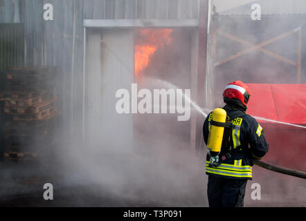 Roggendorf, Germany. 11th Apr, 2019. A firefighter extinguishes a major fire in a peat factory. Several warehouses and production halls have gone up in flames there. Credit: Daniel Bockwoldt/dpa/Alamy Live News Stock Photo