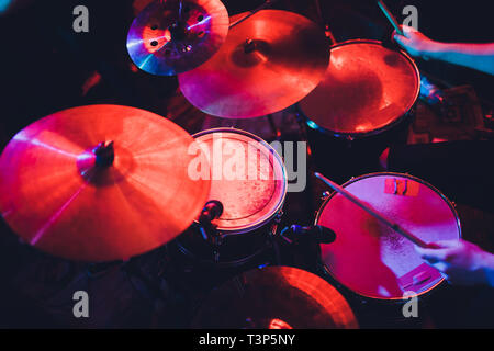 Drummer playing drum set at concert on stage. Music show. Bright scene lighting in club,drum sticks in hands Stock Photo