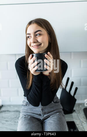 Happy woman drinking tea in the kitchen at home. Stock Photo