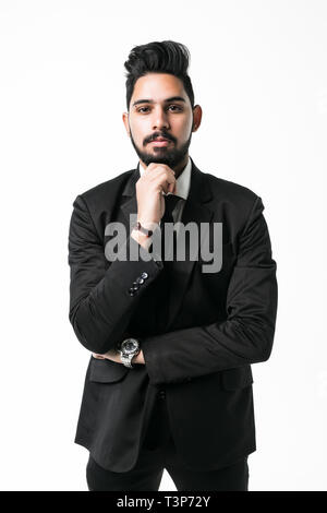Thoughtful young indian man in shirt and tie looking away and touching his chin while standing against white background Stock Photo