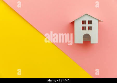 Simply minimal design with miniature white toy house isolated on yellow and pink colourful trendy modern pastel background. Mortgage property insuranc Stock Photo