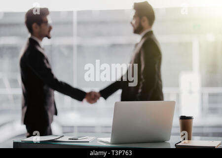 Two business people shaking hands in office as sign of partnership Stock Photo