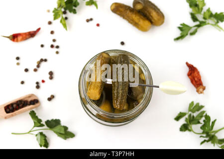Homemade pickled cucumbers in a glass jar on a white background, top view Stock Photo