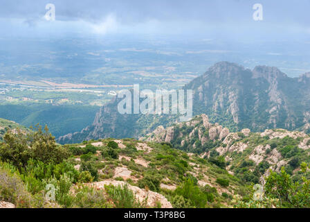 Hazy unusual mountains with green trees and cloudy sky near Montserrat Monastery,Spain. Catalonia Stock Photo