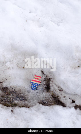 Stockholm, Sweden 7 april 2018. Dirty "Little trees"-tree in the colors of the american flag lies in the snow on the late winter days with melting sno Stock Photo