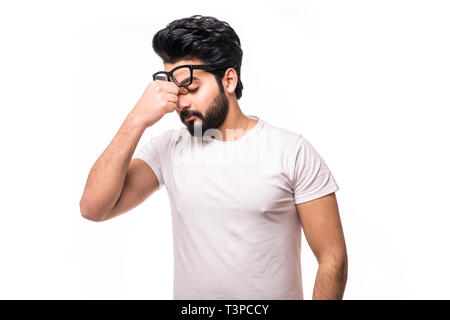 Portrait of tired ordinary european guy with bristle, holding glasses while rubbing eyes, being exhausted and wanting to get rest against gray backgro Stock Photo
