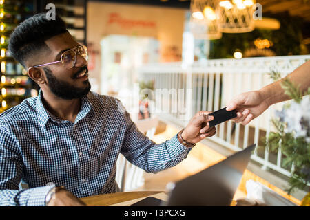 Cropped image of businessman in cafe is paying via the credit card. Stock Photo