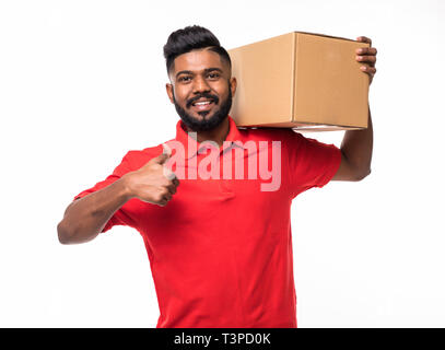 smiling delivery man in blue uniform carrying packages while gesturing thumb up sign isolated on white background Stock Photo