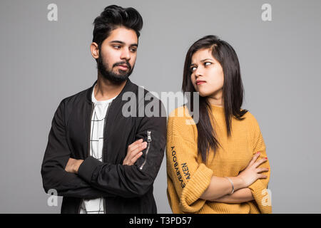 Beautiful indian couple standing apart from each other while being in a quarrel on grey background. Stock Photo