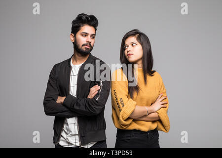 Beautiful indian couple standing apart from each other while being in a quarrel on grey background. Stock Photo