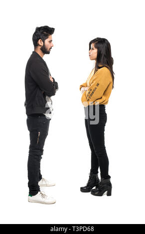 Beautiful indian couple standing apart from each other while being in a quarrel look each other on grey background. Stock Photo