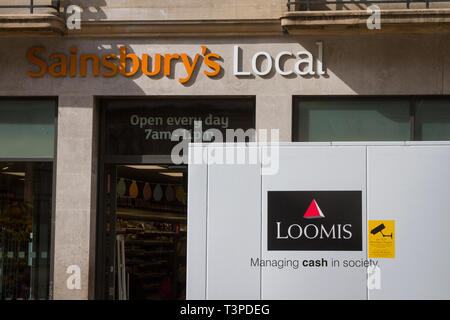 The side of a Loomis UK Ltd. security van with a live CCTV recording warning, parked in front of Sainsbury's Local in Oxford Stock Photo