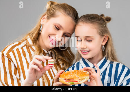 Appealing good-looking positive girls comparing different sizes of burgers Stock Photo