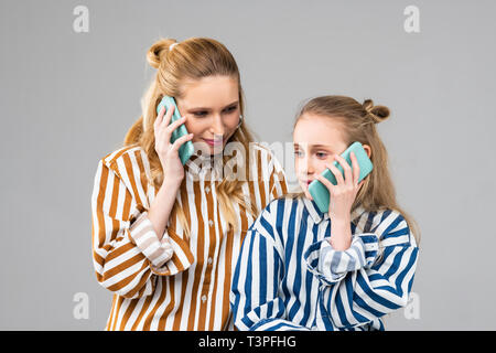 Busy positive girl of different ages talking on mobile phones Stock Photo