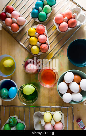 Dyeing eggs for Easter holidays, coloring with different color and tonality using food colorant over a gray concrete background Stock Photo