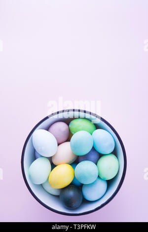 Colored eggs with pastelle tones inside a metallic bowl over a pink background, back lighted,  easter concept,holiday. Stock Photo