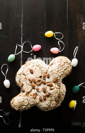 Colomba pasquale , dove, with multi colored eggs and on a wooden dark background, top view, natural window light. Stock Photo