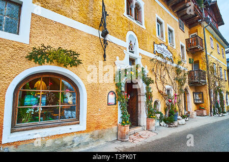 HALLSTATT, AUSTRIA - FEBRUARY 21, 2019: The cozy restaurant in historic mansion in Seestrasse embankment is decorated with sculpture, vintage sign and Stock Photo
