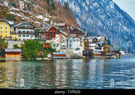 Hallstatt has traditional architecture for Salzkammergut region, its small colored houses with wooden roofs and balconies are densely built on Salzber Stock Photo