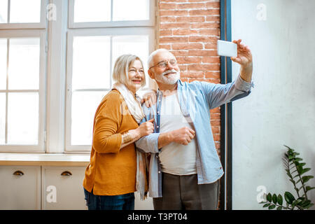 Happy senior couple making selfie photo or talking online using smart phone at home Stock Photo