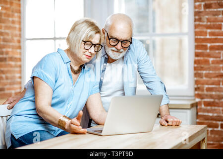 Happy senior couple shopping online using credit card and laptop at home Stock Photo