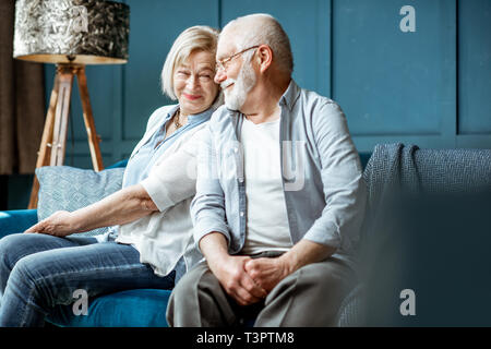 Lovely senior couple dressed casually having fun, sitting together on the couch at home Stock Photo