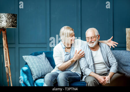Lovely senior couple dressed casually having fun, sitting together on the couch at home Stock Photo