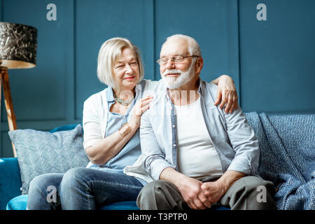 Lovely senior couple dressed casually having fun, sitting together on the couch at home Stock Photo