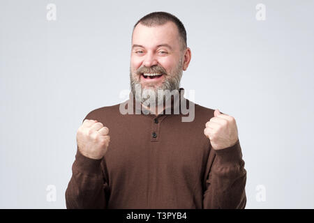 mature european man raising fists up celebrating his success. Stock Photo